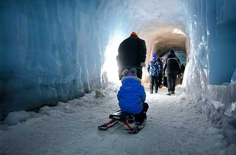 Father taking little girl on sled on a tour inside the glacier tunnel 1050x700 achc7i